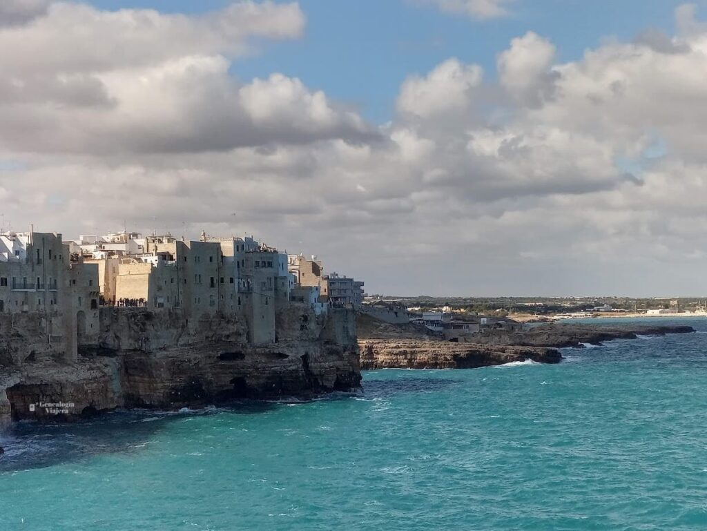 Vista del mar turquesa de Polignano a Mare con el casco histórico de la ciudad sobre los acantilados al fondo, en la costa de Puglia, Italia.