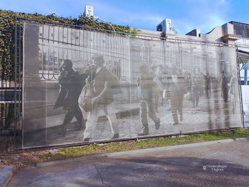 Mural histórico de inmigrantes llegando a Argentina con equipaje después de su viaje en barco