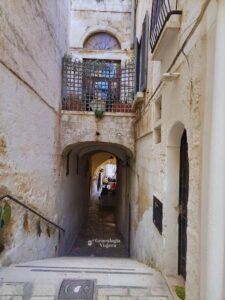 Callejón del centro histórico de Polignano a Mare con escaleras, arcos de piedra y casas blancas típicas de Puglia