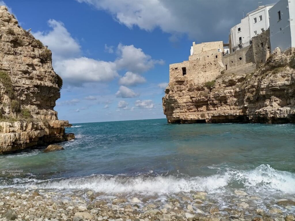 Vista de Cala Porto en Polignano a Mare con la playa de piedras blancas, aguas turquesas del mar Adriático y acantilados rocosos