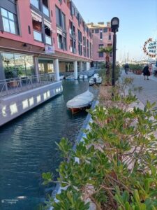 Pequeño canal del Porto Antico de Génova con una embarcación amarrada y edificios portuarios al fondo.