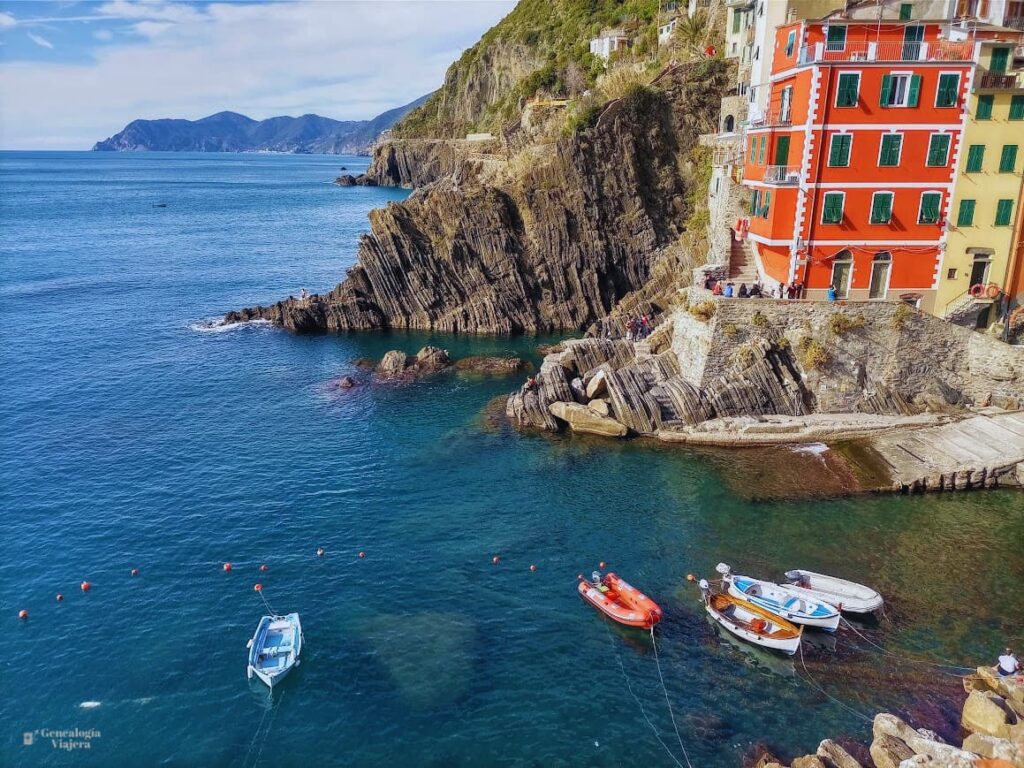 Puerto de Riomaggiore con pequeñas embarcaciones, el mar y las tradicionales casas de colores construidas sobre la ladera de la montaña.
