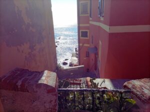 Vista del mar Mediterráneo desde un pasaje elevado de Boccadasse, enmarcado por las coloridas casas del histórico barrio marinero de Génova.