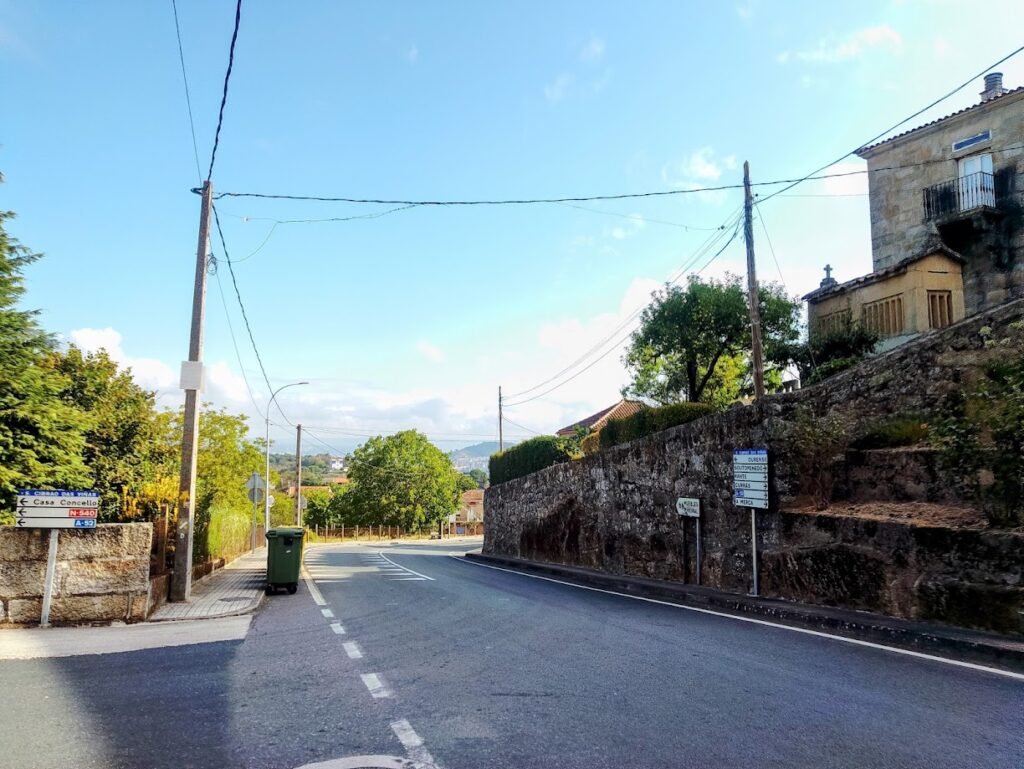 Cartel del Concello y ruta junto a una casa con hórreo en San Cibrao das Viñas
