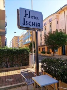Hotel Ischia en Rimini, con una mesa en la vereda y edificios de la calle