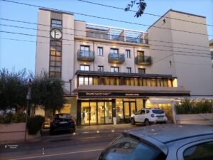 Fachada del Ferretti Beach Hotel en la zona marina de Rímini, mostrando una estructura de líneas modernas combinada con balcones tradicionales de la arquitectura hotelera clásica de la costa italiana.