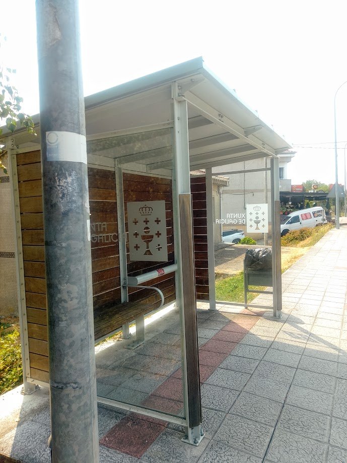 Interior de una marquesina de autobús moderna con el logotipo oficial de la Xunta de Galicia impreso en el cristal en Sandiás