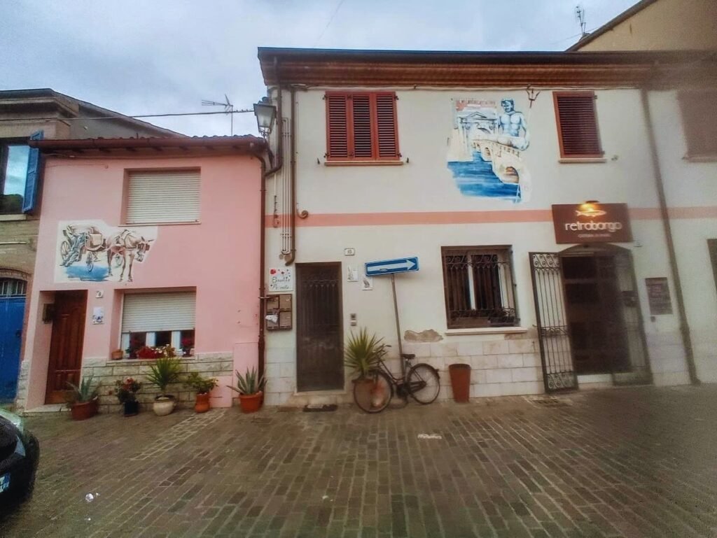 Fachadas de casas tradicionales con murales pintados y adoquines en el histórico Borgo San Giuliano de Rímini.