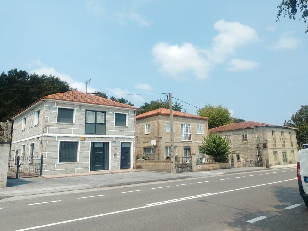Hilera de casas modernas de dos plantas con fachada de piedra junto a la carretera en Sandiás, Ourense