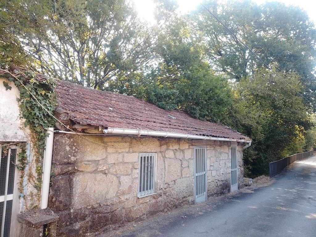 Primer plano de los gruesos muros de piedra granítica de una casa tradicional rústica en el casco histórico de Melón, Ourense.