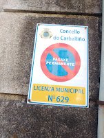 Cartel de vado permanente en una pared de piedra con la inscripción oficial del Concello do Carballiño y el escudo municipal.