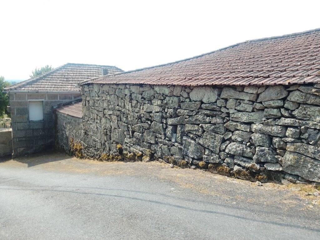 Calle asfaltada en Vilar de Santos y casas tradicionales con tejados de tejas.