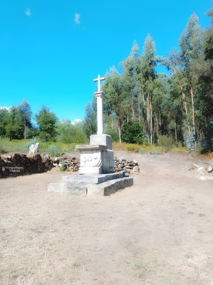 Antiguo cruceiro de piedra tallada sobre un pedestal en un claro rodeado de árboles y naturaleza en O Carballiño, Galicia