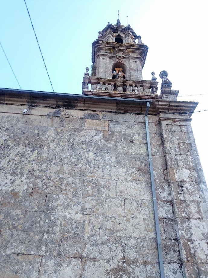 • Frontón triangular de piedra tallada sobre la puerta principal de la iglesia de Corneda, con un relieve de Santiago Apóstol en una hornacina central.