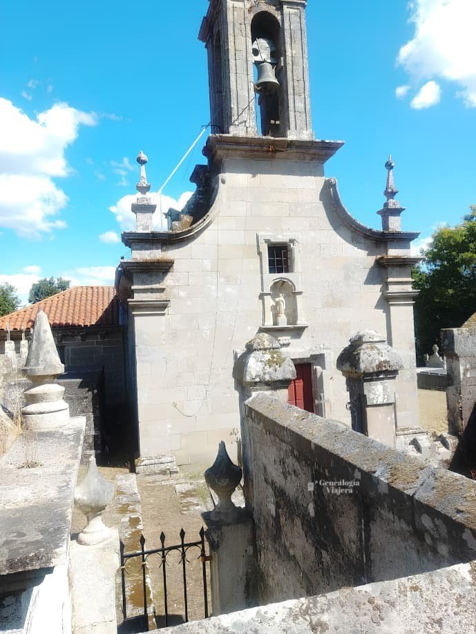 Vista exterior de la Iglesia de Santa Baia de Banga en O Carballiño, mostrando sus muros de sillería de piedra, el recinto amurallado y el acceso de reja metálica cerrado.