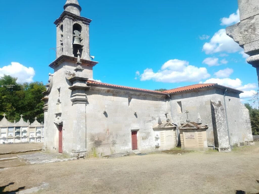 Vista frontal de la fachada barroca de la iglesia de Santa Baia de Banga con su hornacina, detalles en piedra y campanario elevado.