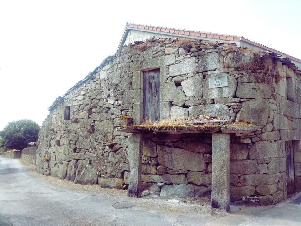 Antigua edificación de piedra con escalinata y un porche sostenido por columnas rústicas en la Rúa da Senra en Vilar de Santos.