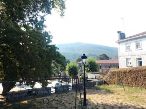 Sector recreativo infantil con hamacas y anillas cerca del Monasterio de Melón, mostrando un entorno de árboles y montañas al fondo.