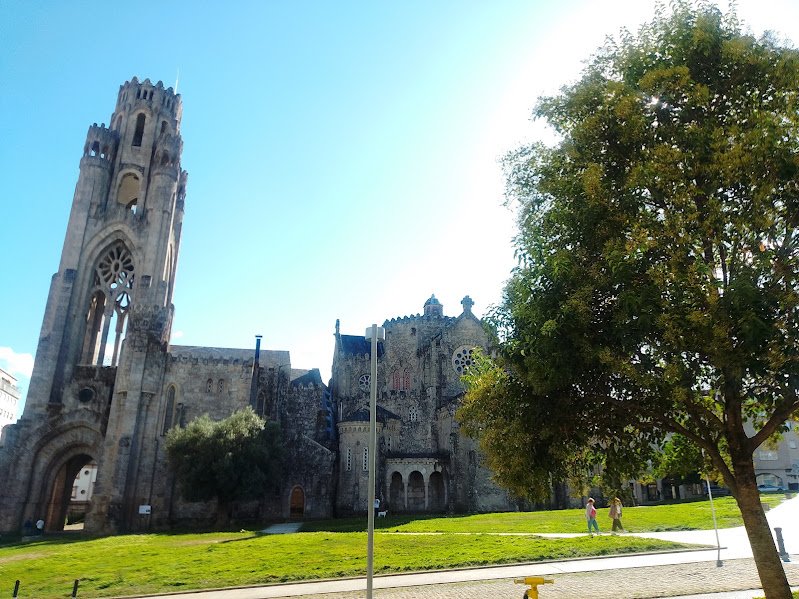 Templo de la Vera Cruz de O Carballiño diseñado por Antonio Palacios, mostrando su imponente torre calada y jardines laterales bajo un cielo despejado.
