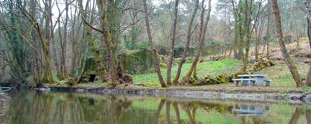 Río Barbadás junto a antiguos molinos de piedra abandonados y mesas de un área recreativa en el espacio natural de A Boutureira, San Cibrao das Viñas.