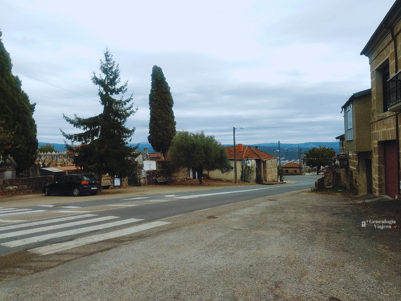 Calle de cemento en Paradela con un poste de luz de madera que conduce hacia la zona del cementerio y la parada de autobús.